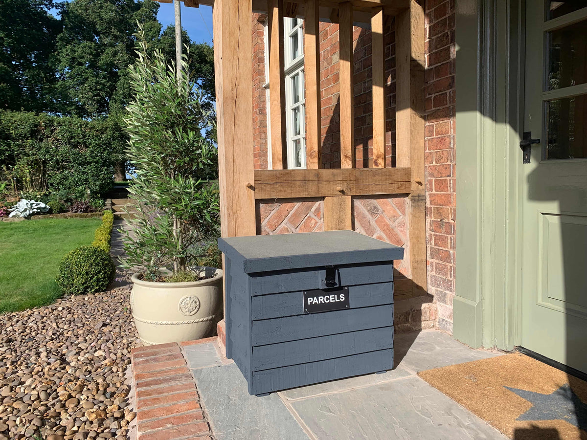 Dark Grey DelSafe wooden parcel delivery box beside a timber garden porch