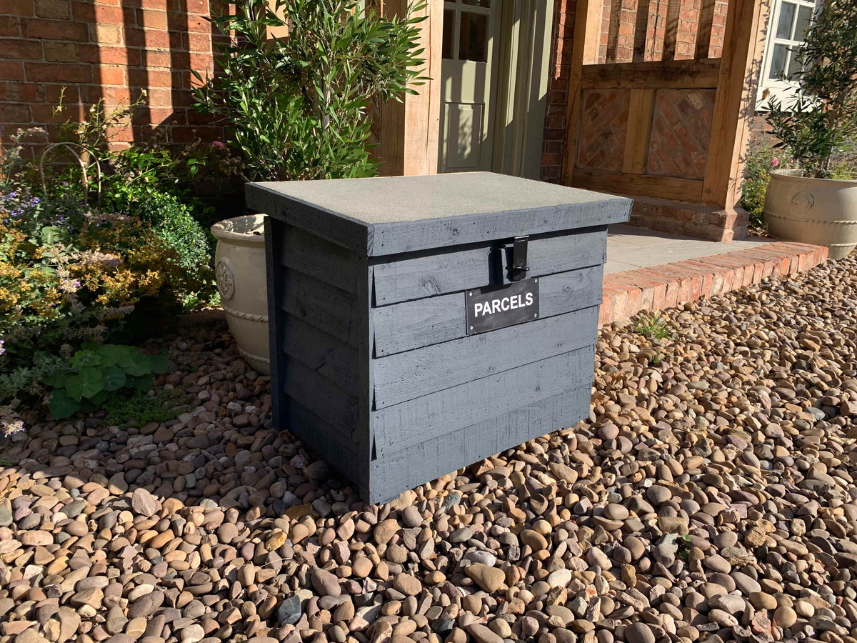 Dark Grey DelSafe wooden parcel delivery box with grey felt roof in a garden setting