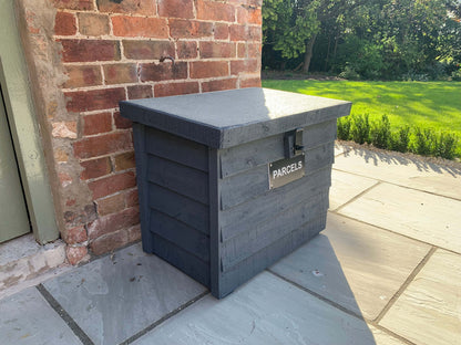 Dark Grey DelSafe wooden parcel delivery box beside a brick wall on a patio