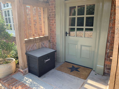 Black DelSafe wooden parcel delivery box beside a front door