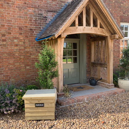 Natural DelSafe wooden parcel delivery box beside a timber garden porch